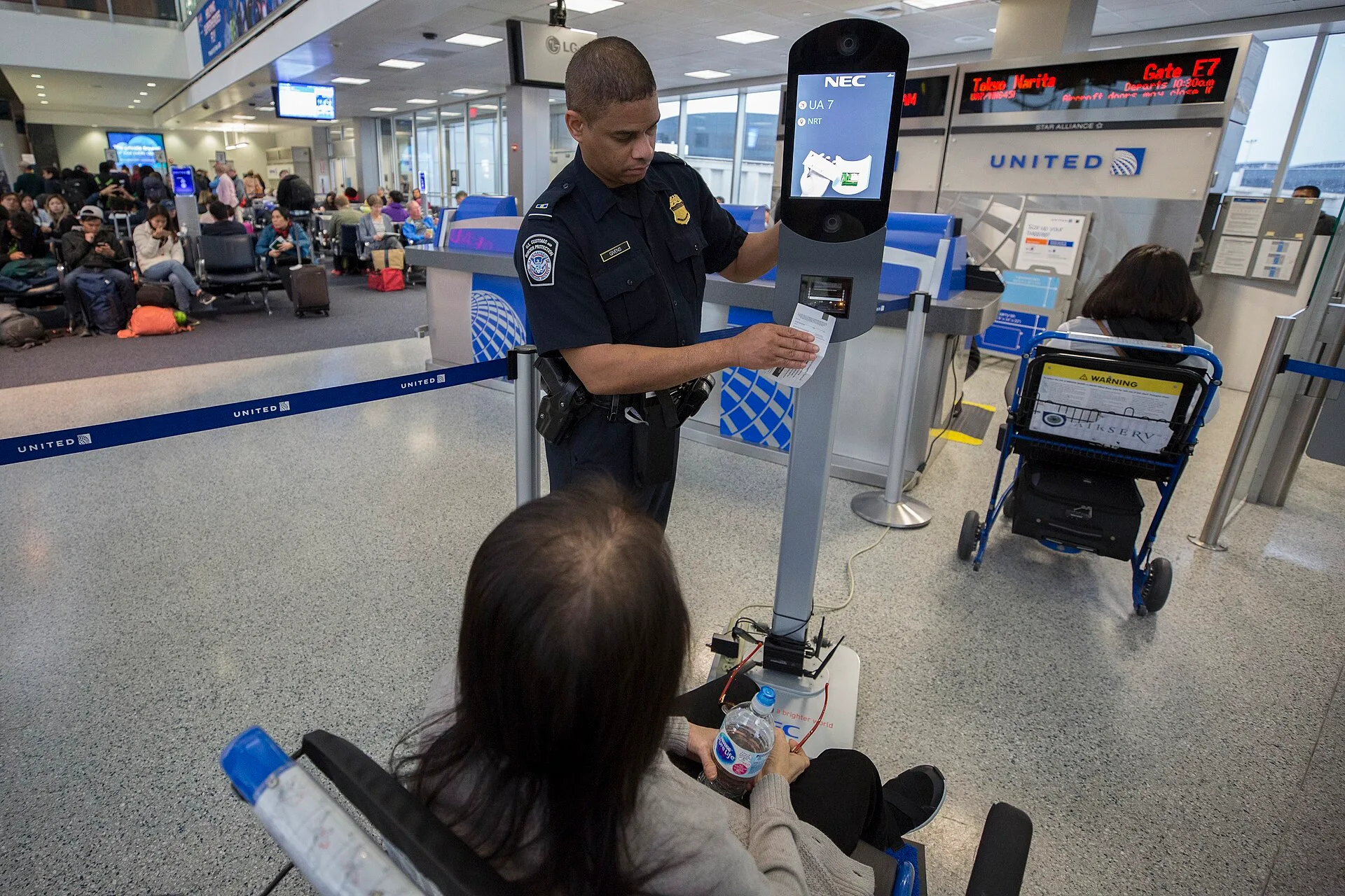 A U.S. Customs and Border Protection, Office of Field Operations, officer assist a passenger with ticket scanning and taking biometric facial recognition photos prior to boarding a flight at Houston International Airport on February 12, 2018. ..Photographer: Donna Burton. Face Match App Illinois Law: The Biometric Question to Ask First